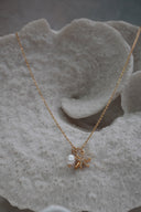 Alternate view: gold-tone necklace with two overlapping starfish charms, clear accents and a white oval bead.