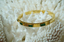 Gold-tone hinged bangle with green rectangular faceted accents.