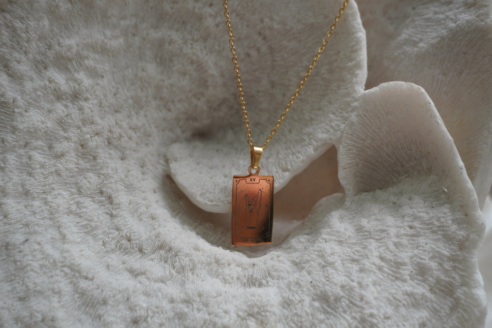 Alternate view: gold-tone chain necklace with a reflective rectangular The Devil pendant, hand-gesture illustration and XV lettering.